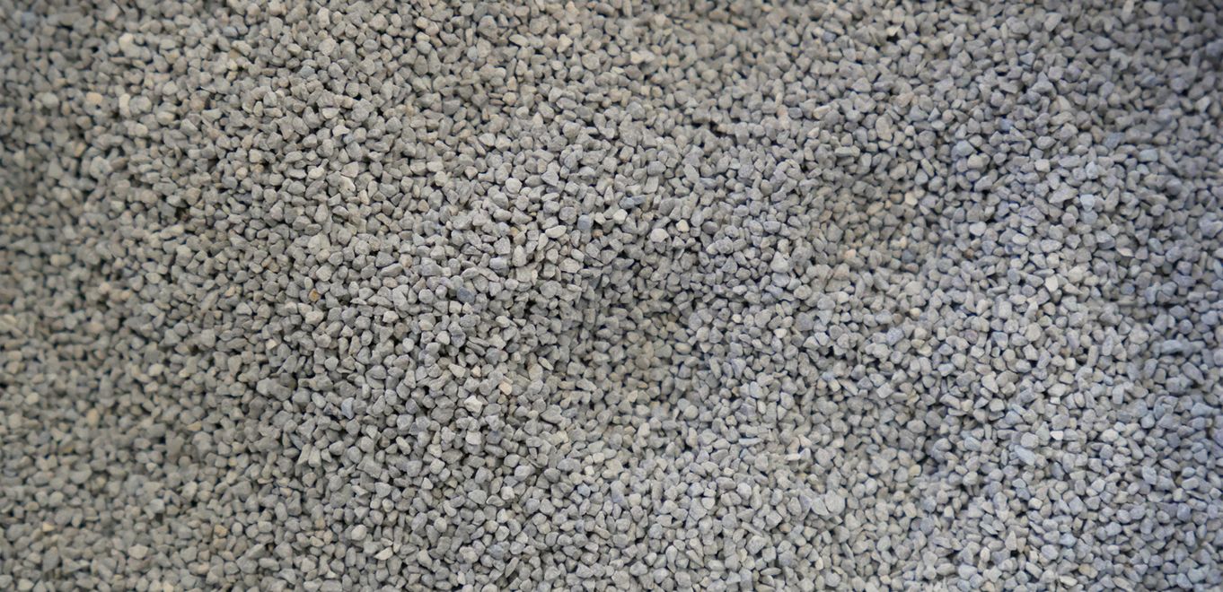 Image: poudre de roche grossièrement granulée, gris moyen et étalée sur une surface plane